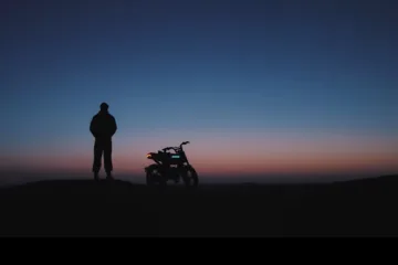 Rider standing next to an AOTOS Flux 26 in the desert at dusk