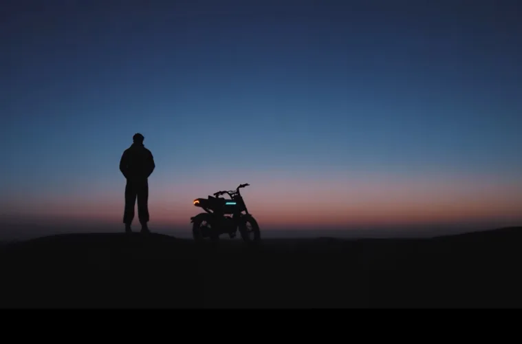 Rider standing next to an AOTOS Flux 26 in the desert at dusk